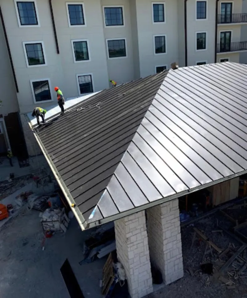 Crew installing standing seam metal roof panels on a commercial project in Lake Norman of Iredell